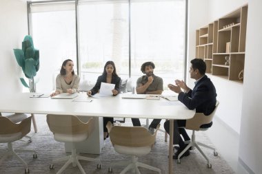 Modern ofis toplantı odasında müzakere eden, iş seminerine katılan, sözleşme detaylarını tartışan, takım çalışması, stratejik planlama veya karar verme üzerine odaklanan dört çok ırklı profesyonelden oluşan bir grup.