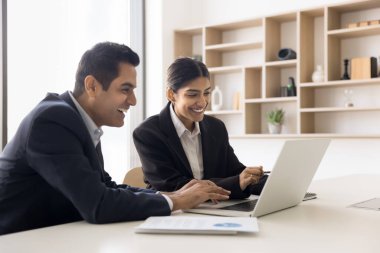 İki iş arkadaşı, genç ve olgun Hintli meslektaşlar, dizüstü bilgisayarlarını kullanarak birlikte çalışan profesyoneller, iş birliği yapan, gülümseyen, tartışan, ortak görevi gözden geçiren, proje veya yeni program