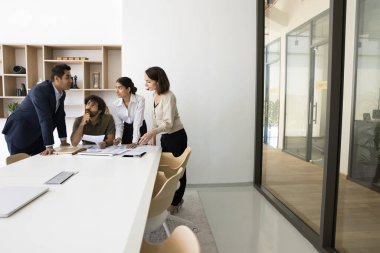 Çok uluslu dört takım arkadaşı ticareti çözüyor, stratejik karar verme için modern konferans odasında toplanıyor, mali raporları gözden geçiriyor, öngörü ve planlama stratejilerini gözden geçiriyorlar. Takım çalışması.