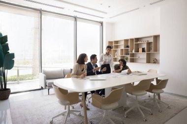 Parlak, modern ofis yönetim kurulunda işbirliği yapan profesyonellerden oluşan bir grup, konferans masasının etrafında oturdular, belgeleri incelediler ve fikirler, takım çalışması ve verimliliği tartıştılar.