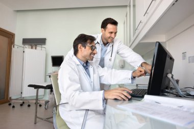 Klinikte takım çalışması yapan iki gülümseyen doktor, iş arkadaşından onay ya da tavsiye isteyen meslektaşlar, tedavi planı ve seçeneğini birlikte değerlendirmek, son tıbbi çalışmalar hakkındaki görüşleri paylaşmak