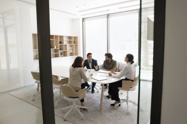 Çok uluslu iş adamları ve iş kadınları beyin fırtınası, strateji planlaması veya sorun çözme tartışmalarına katılıyor, yeni fikirler geliştiriyor, çizelgeleri gözden geçiriyor, toplantı sırasında birlikte evrak işleriyle uğraşıyorlar.