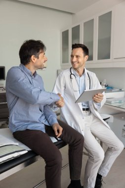 Tatmin olmuş orta yaşlı bir hasta tedavi planı üzerinde uzlaşılmış durumla ilgili net bir açıklama aldı, beyaz üniformalı profesyonel terapist veya kardiyolog ile tokalaştı. Başarılı bir iyileşme