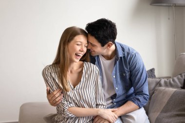 Çift kanepeye oturur, güler, neşeli ve samimi anlar paylaşır, mutluluk ve sıcaklık saçar. Sevgi dolu bir adam evdeki kanepede oturan sevgilisini kucaklıyor. Romantik ilişkiler, tatiller.