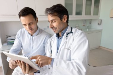 Tıbbi bilgi, laboratuvar sağlık testi sonuçları ve erkek hastaya tedavi planlarını sunmak için elinde tablet bulunan terapist. Tıbbi bakım, teknoloji, e-sağlık hizmetleri