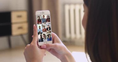 Akıllı telefon, internet bağlantısı ve video konferans uygulaması kullanarak uzak iş ya da kişisel iletişim. Çok ırklı insanlar grup video etkinliğine katılıyor, kadınların omuzlarının üzerinden bakıyorlar.
