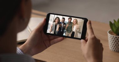 Kadın akıllı telefonu tutuyor, gülümseyen küçük kızıyla görüntülü görüşme yapıyor, cep telefonu ekranını omzunun üstünden görüyor, kapatıyor. Modern kablosuz iletişim teknolojisi ve uzaktan iletişim kullanarak aile içi etkileşim