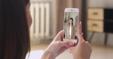 Genç Asyalı kadının yeni evinin anahtarlarını gösterdiği akıllı telefonu tutan kadın, taşınmayı kutluyor, video blogunda kanal içeriği için harika haberler paylaşıyor. Sosyal medya platformu kullanıcısı