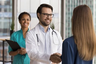 Birlikte iyileşmeyi kutluyoruz. Gülümseyen genç adam doktor mutlu kadın hastayla tokalaşıyor başarılı tanı rehabilitasyonundan sonra etkili tedavi kursundan yardım için güven takdir ediliyor.