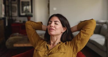 Gülümseyen Latin kadın ellerini rahat koltuğa yaslayıp temiz hava soluyor, rahat bir dairede dinleniyor, gözleri kapalı gündüz uykusunun tadını çıkarıyor. Boş zaman, rahatlama.