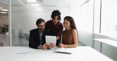 Ofiste dijital tablet kullanan, pazarlama stratejisi planlayan, hedef kitleleri, kampanya performansını veya yaklaşan görevleri tartışan, yeni ürün fikirlerini veya ilerlemeyi gözden geçiren üç farklı takım arkadaşı