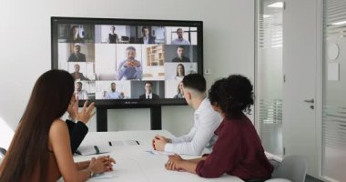 İş ortakları grubu, çok uluslu profesyoneller konferans odasında toplandılar, küresel takım çalışmasına katıldılar, genç Arap bir adamın konuşmasını dinlediler, video aracılığıyla görüşmelere katıldılar.