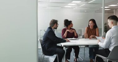 Çok ırklı takım arkadaşları, ortak görevi tartışmak, sunum hazırlamak, fikir alışverişinde bulunmak, yaratıcı görüş ve çözümlerin alışverişinde bulunmak, stratejik kararlar planlamak veya pazarlama kampanyası düzenlemek üzere toplantı masasında toplandılar.