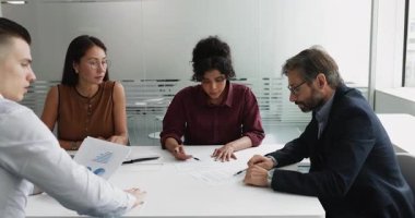 Profesyonel anlaşma, başarılı iş ortaklığı, güven, ortaklık. Bir grup iş ortağı modern ofiste masanın etrafında otururken, iki takım üyesi sözleşme imzaladı ve el sıkıştı.