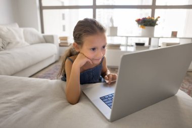 Çocuklar için dijital yaş tehlikesi. Meraklı genç kız evde tek başına vakit geçiriyor. Ekran surf sosyal medya içeriğine odaklanmış not defteri kullanıyor. İnternet uygulamasında ebeveyn kontrolü olmadan online oyun sohbeti yapıyor.