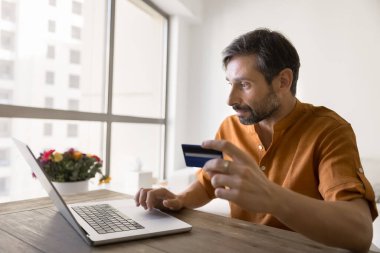Uzaktan mali yönetim. Olgun girişimci masasında oturur ecommerce web sitesinden mal satın alır iş ödemelerini gözden geçirir banka hesap transferlerini ev ofisinin not defteri kredi kartıyla yapar.