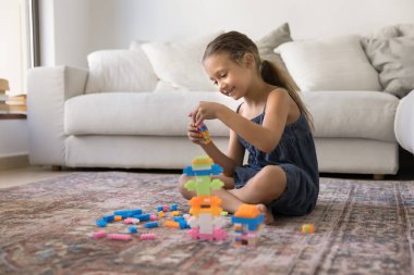 Hayal kuruyorum. Mutlu gülümseyen ergen kız evde tek başına oynuyor sıcak zeminde oturmuş renkli inşaat malzemelerinin fantezi kulesini yaratıyor oyun saatlerinde yaratıcı aktivitelerin tadını çıkarıyor. Boşluğu kopyala