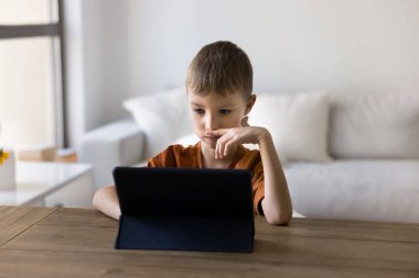 Etkileşimli öğrenme. Evden mesafelere odaklanmış çocuk okul çocuğu eğitimi tablet bilgisayar ekranından elektronik kitap okuyarak sanal sınıfa katılıyor.