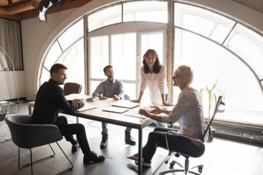 Mutlu bayan lider yönetici ofis toplantısındaki proje sunumunda iş arkadaşlarıyla gülüyor. Uluslararası profesyonel girişim patronu çeşitli yönetim kurullarına sesleniyor. Şirket çalışanları.