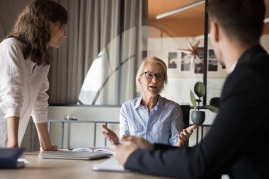 Orta yaşlı CEO profesyonel iş kadını çeşitli grup proje yöneticileri ekibinin konferans odasında atölye çalışması yapıyor. 60 'ların koçu danışman müşteriler, finansal pazarlama şirketi stratejisi geliştirin