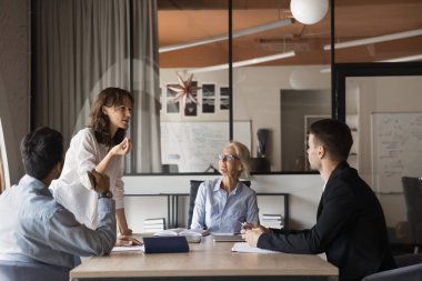 Profesyonel yöneticiler konferans masasında birlikte çalışıp konuşuyorlar. Güzel bayan lider CEO projeyi açıklıyor, çeşitli yönetim kurulu iş adamlarına ofis ekibine konuşuyor.