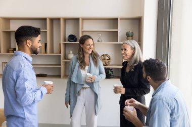 Dostça bir ortaklık. Keyifli, çok uluslu iş arkadaşlarıyla sohbet etmek rahat yaratıcı çalışma alanı planında kahve molası sırasında başlangıç fikrini tartışmak evrak işlerinde şakalaşmak eğlenceli