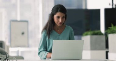 Ofiste dizüstü bilgisayarda tek başına yazı yazan, çeneye dokunan, kurumsal internet iletişimi için yaratıcı bir fikir düşünen, mutlu olan, gülümseyen genç Latin iş kadını.