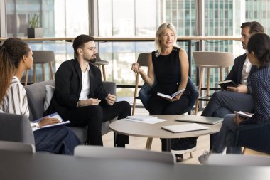 Grup eğitimi. Orta yaşlı kadın profesör hoca eğitim semineri düzenliyor. Modern toplantı odasında çeşitli etnik çeşitlilikteki öğrenciler için eğitim semineri düzenleniyor.