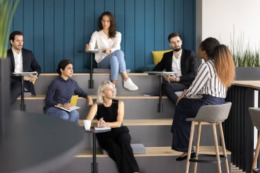 Derste sunuyorum. Amphitiyatroda toplanan çok kültürlü iş adamı grupları seminer sınıfı atölyelerine katılıyor. Genç bayan öğretmen eğitmenini dinleyin.