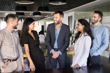 Bir grup mutlu takım arkadaşı birlikte çalışıyor, neşeli ve neşeli bir sohbete girişiyor, gülüyor, birlik hissi yayıyor, mola sırasında ya da takım oluşturma etkinliği sırasında arkadaşça etkileşimlerin keyfini çıkarıyor.