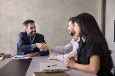 Mutlu orta yaşlı işadamı iş ortağının elini sıkıyor konferans odasında takım toplantısını bitiriyor. Sözleşme imzalama, anlaşma yapma, işbirliği veya başarılı müzakere tamamlama jesti