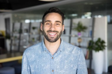 Mutlu İspanyol iş adamı, girişimci ya da serbest çalışan, ofiste kameraya neşeli bir ifadeyle poz veren, pozitiflik ve başarı sergileyen fotoğrafçı. İşçi portresi.