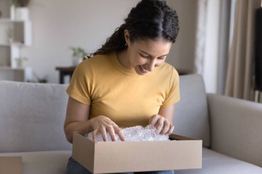 Kutudaki mutluluğu. Gülümseyen genç bayan ecommerce pazarı müşterisi kanepeye otur büyük bir karton kutu aç posta yoluyla gelen siparişlerin tadını çıkar hediyelerle birlikte paketleri aç