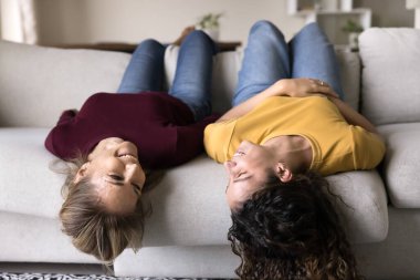 Tepetaklak eğleniyorum. Sevimli orta yaşlı anne gen z genç kız kanepede başları öne eğik uzanmış sohbet evde dinlenme keyfine varın neşeli, pozitif ruh hali içinde özgürlüğün tadını çıkarın