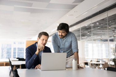 Çalışma ofisinde dizüstü bilgisayarı kullanan, yeni platformu gözden geçiren, beyin fırtınası yapan, yaratıcı çözümler ya da iş stratejileri üreten, görev ya da çevrimiçi sunum üzerinde çalışan iki çok uluslu erkek arkadaş