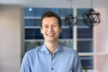 Sıradan mavi gömlekli 30 'lu yaşların genç iş adamı gülümseyen, iyimser bir ifadeyle kameraya bakıyor, özgüven ve profesyonellik saçıyor. Banka danışmanı, yönetici ya da CEO, ofis portresi