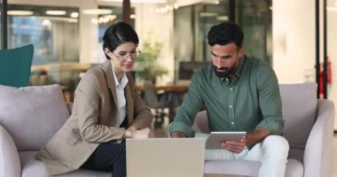 Çok ırklı genç iş arkadaşları ürün geliştirme, çevrimiçi proje büyümesi, dizüstü bilgisayar ve tablet kullanma, ofis iş arkadaşı lobisinde konuşma, kahkahalar.