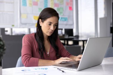 Veri incelemesi ve analiz. Milenyum kadın ofis çalışanı muhasebeci iş yerinde oturup şirket uygulamasını kullanarak dijital evrak işleriyle uğraşan bir defter hazırlamakla meşgul.