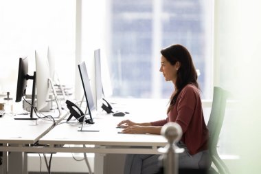 İşbirlikçi uzayda tek başına çalışmak. Genç ve meşgul bayan şirket çalışanı yazılım geliştirici, yakınlardaki boş işyerleri ile birlikte, yenilikçi açık uzay ofisinde, masaüstü bilgisayarında yalnız çalışıyor.