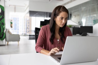 Çalışmalar devam ediyor. Günümüz açık planlama ofisinde defter üzerinde çalışan meşgul genç bayan profesyonel yönetici web yazma e-postasında kurumsal uygulama tarayıcı verilerinde elektronik belge oluşturur. Boşluğu kopyala