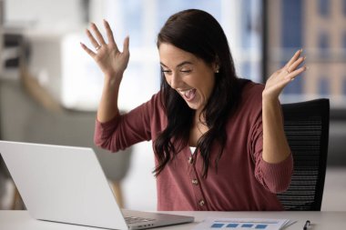 Heyecanlı bir profesyonel. Neşeli ve coşkulu genç iş kadını serbest çalışan girişimci el çırpıyor iş zaferini kutluyor defter ekranına bakın sorun çözülmüş büyük sonuçların keyfini çıkarın