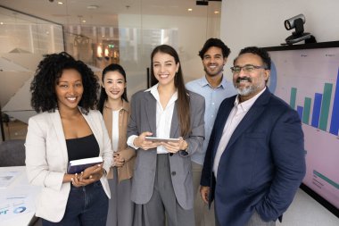 Çeşitli beş iş adamından oluşan bir grup, modern konferans odasında, kameraya bakıp, gülümseyen, olumlu takım çalışması yapan, güçlü takım ruhu yayan bir grup. Profesyonellik, işbirliği