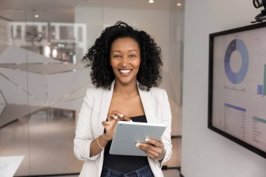 Afrikalı iş kadını, proje yöneticisi, pazarlama departmanı çalışanı ekranın yanında duruyor, dijital tablet üzerinde yeni yenilikçi iş platformu veya araçlar kullanarak,