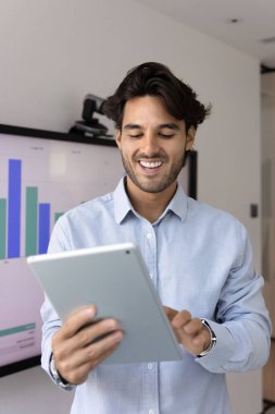 Ofiste dijital tablet üzerinde çalışan, dosya veya belgeleri düzenleyen, proje yönetim araçlarına erişen, notları veya gündemleri kontrol eden, proje güncellemelerini izleyen, memnun hisseden gülümseyen profesyonel işadamı