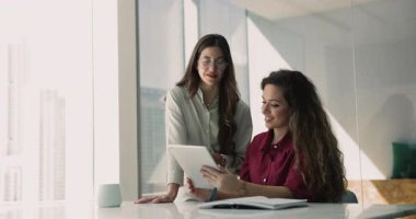 Tablette online ürünü tartışan iki mutlu bayan meslektaşımız, takım çalışması için dijital cihaz kullanıyorlar, profesyonel tartışma. İnternet proje yöneticisi danışma uzmanı istiyor