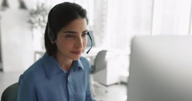 İş yerindeki büyük ekranda mikrofon okuma içeriği olan kablosuz kulaklıklı müşteri destek merkezi yöneticisi kadın, çeneye dokunuyor, istemci talebi üzerine düşünüyor