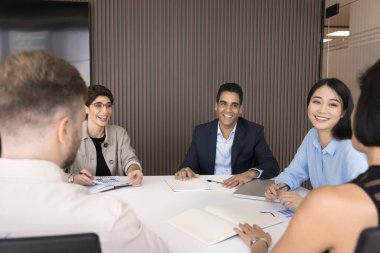 Çeşitli takım arkadaşları konferans masasında toplanan atölyeye ya da eğitim toplantısına katılıyor, gülüyor ve modern ofisteki şirket brifinglerinde arkadaşça etkileşimin keyfini çıkarıyorlar. Takım çalışması, takım oluşturma
