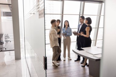 Profesyonel bir grup, modern kurul odasında duruyor, fikirleri paylaşıyor, işle ilgili konuları tartışıyor, görüşlerini ve noktalarını dile getiriyor, görevdeki brifing veya seminer etkinliğine katılıyor.