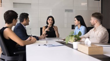 Çekici iş kadını ve takım arkadaşları, devam eden projenin sunumunda işbirliği yapar, durumunu analiz eder, sonraki adımları tartışır, konferans masasında toplanan geri bildirim ve planlama iyileştirmeleri sunar.