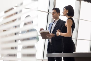 Genç ve olgun profesyonellerden oluşan bir grup işle ilgili bir tartışma içinde, modern ofiste cam duvarın arkasında birlikte duran resmi bir sohbet yürütüyorlar. Profesyonellik, iletişim, takım çalışması